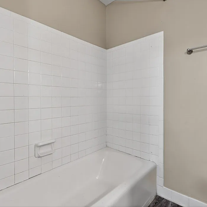 Elegant bathroom with pristine white tiles and inviting bathtub, perfect for a relaxing retreat.