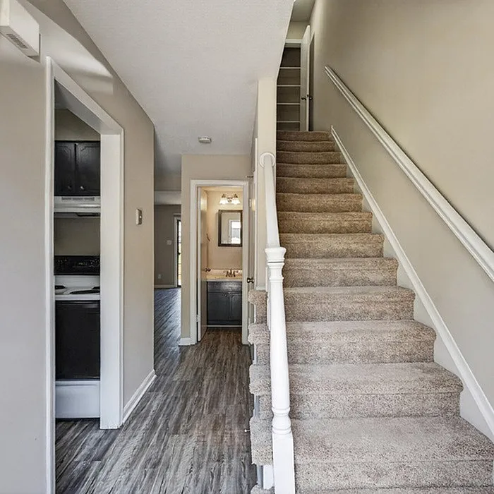 Inviting hallway with elegant staircase, leading to a cozy bathroom and modern kitchen.