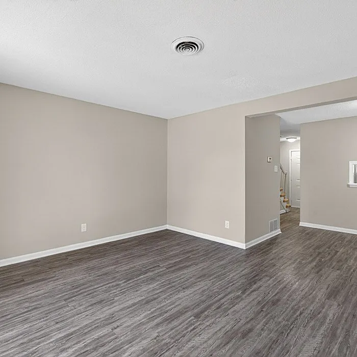 Spacious and modern open-plan living area with elegant wood-style flooring and soft neutral walls, perfect for versatile decor.
