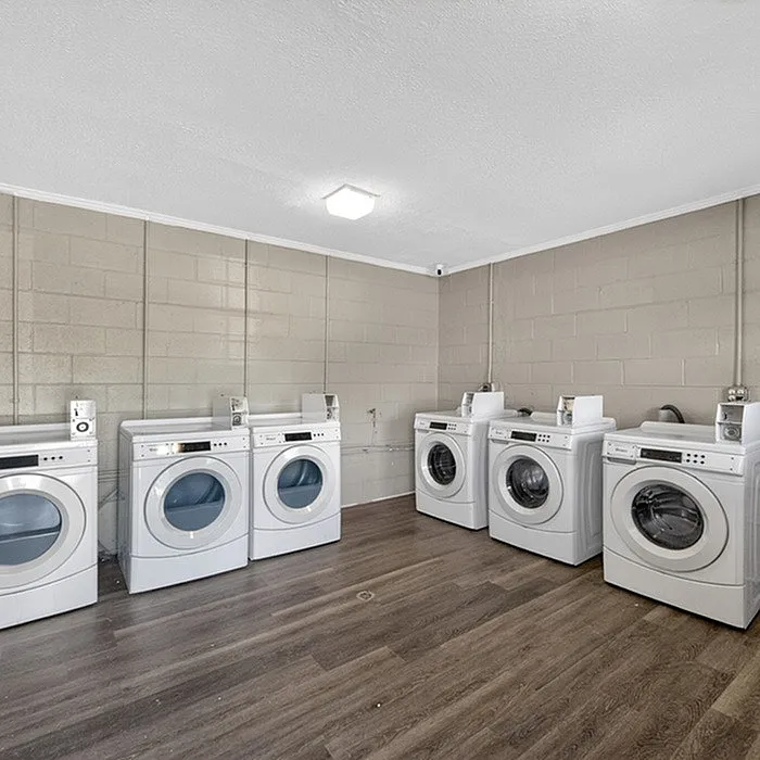 Modern communal laundry room equipped with multiple washers and dryers, featuring sleek machines and a clean, spacious design.