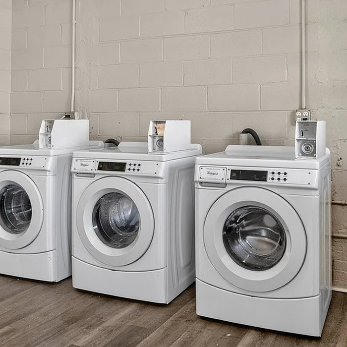 Modern laundry room with three sleek washing machines set against a minimalist backdrop, offering convenience and efficiency.