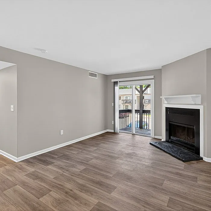 Elegant living room featuring modern hardwood flooring, a cozy fireplace, and sliding glass doors opening to a balcony with a view.