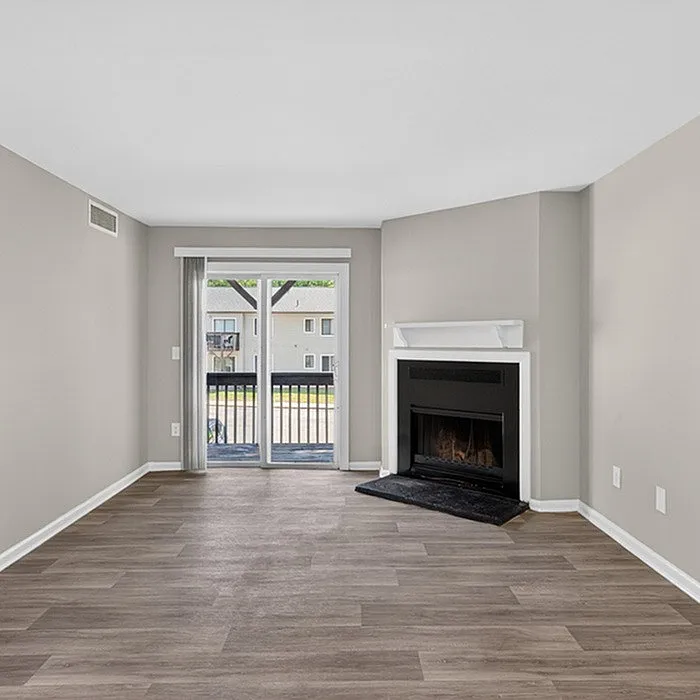 Bright living room with elegant fireplace, sleek wood flooring, and sliding glass doors opening to a scenic balcony view.