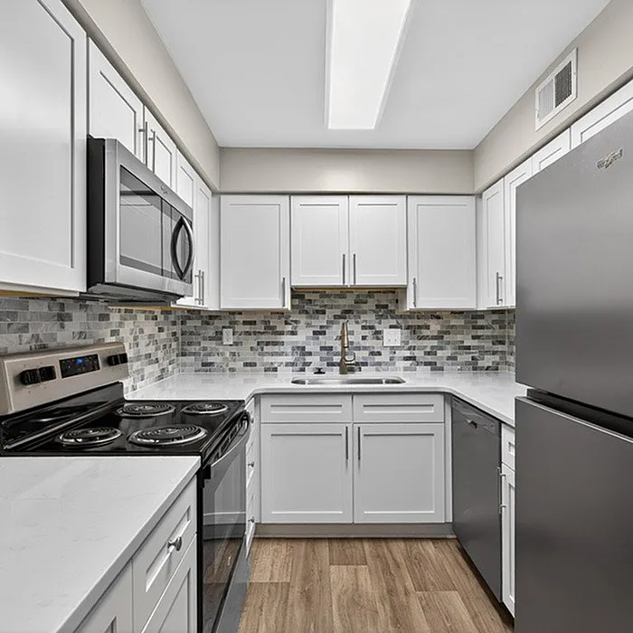 Modern kitchen with sleek stainless steel appliances, elegant white cabinetry, and a stylish mosaic backsplash, creating a bright and inviting space.