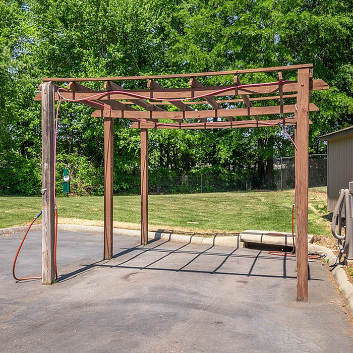Inviting outdoor carport with wooden pergola design in a lush green setting, perfect for summer shade and style.