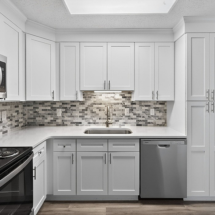 Modern kitchen with sleek white cabinetry, elegant stone backsplash, and stainless steel appliances.