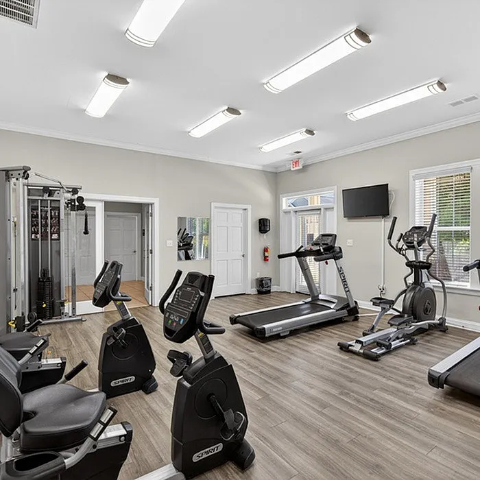 Modern fitness center with state-of-the-art exercise equipment, including treadmills, stationary bikes, and strength machines, in a bright and spacious setting.