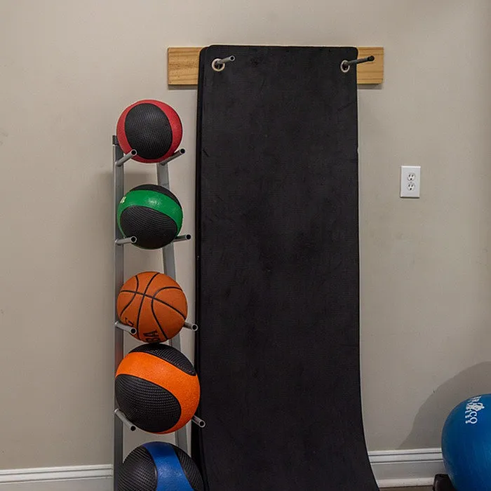 Compact home gym corner featuring a sleek rack with medicine balls and a black exercise mat, ideal for versatile workouts.