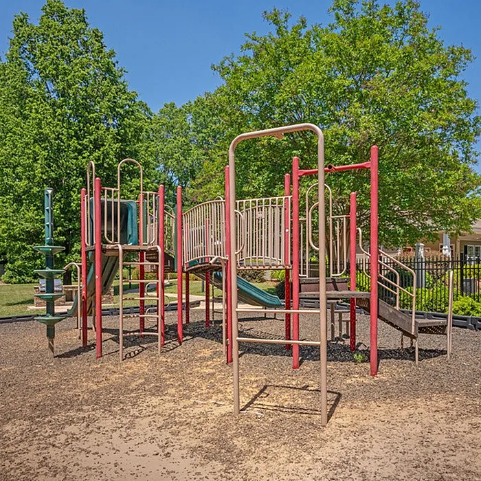 Inviting playground with colorful climbing structures and slides surrounded by lush greenery, perfect for family enjoyment.