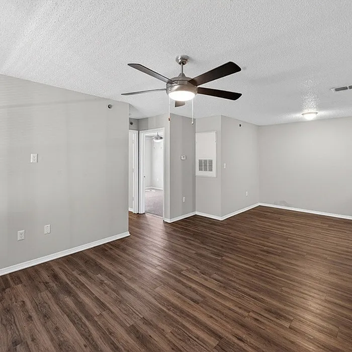Modern apartment with elegant wood flooring and open space, featuring a ceiling fan and ambient lighting.