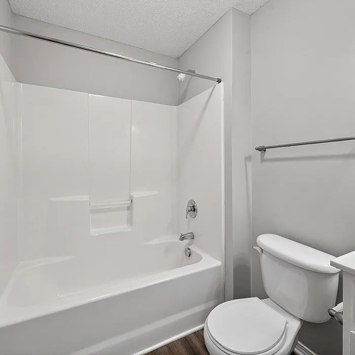 Modern bathroom with sleek white fixtures, a spacious bathtub, elegant tiling, and bright natural lighting.