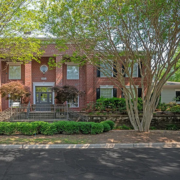 Charming red brick apartment exterior with lush greenery and inviting entrance, perfect for modern living.