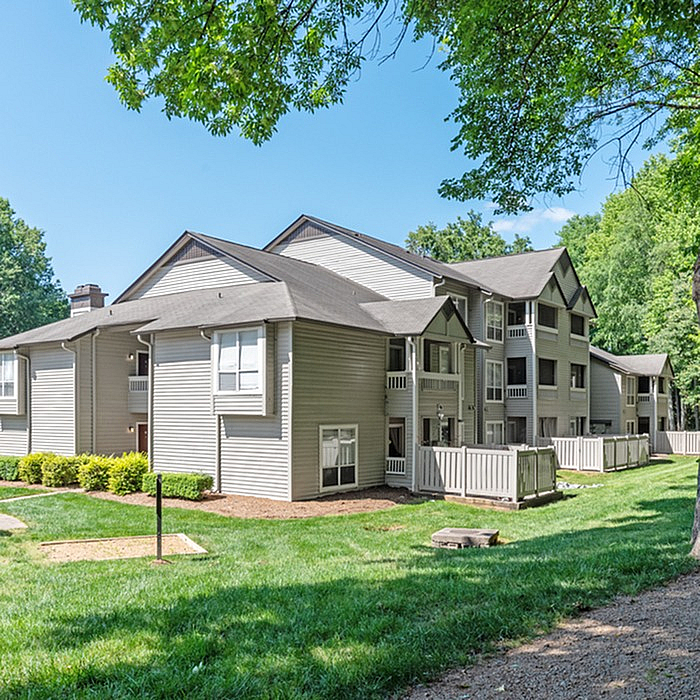 Charming multi-story apartment complex surrounded by lush greenery, offering tranquil living and modern design.