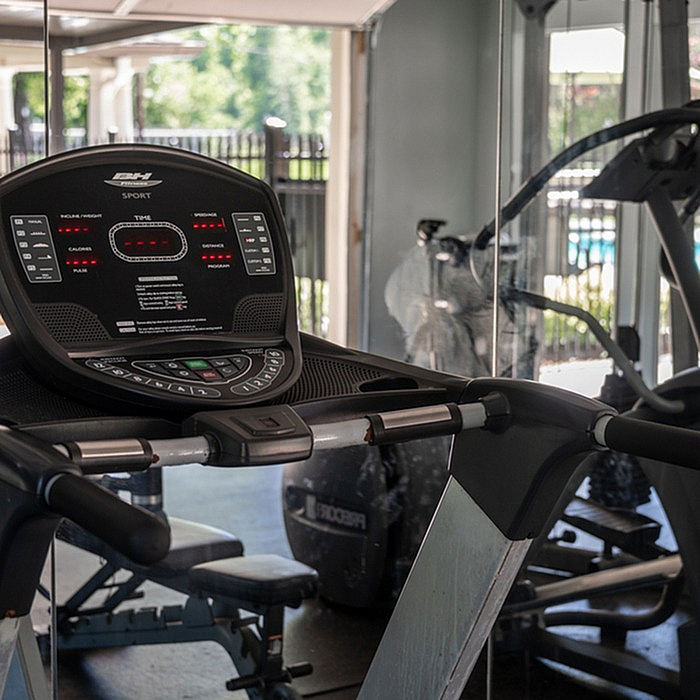 Modern fitness center featuring state-of-the-art treadmill with scenic view of outdoor pool area.