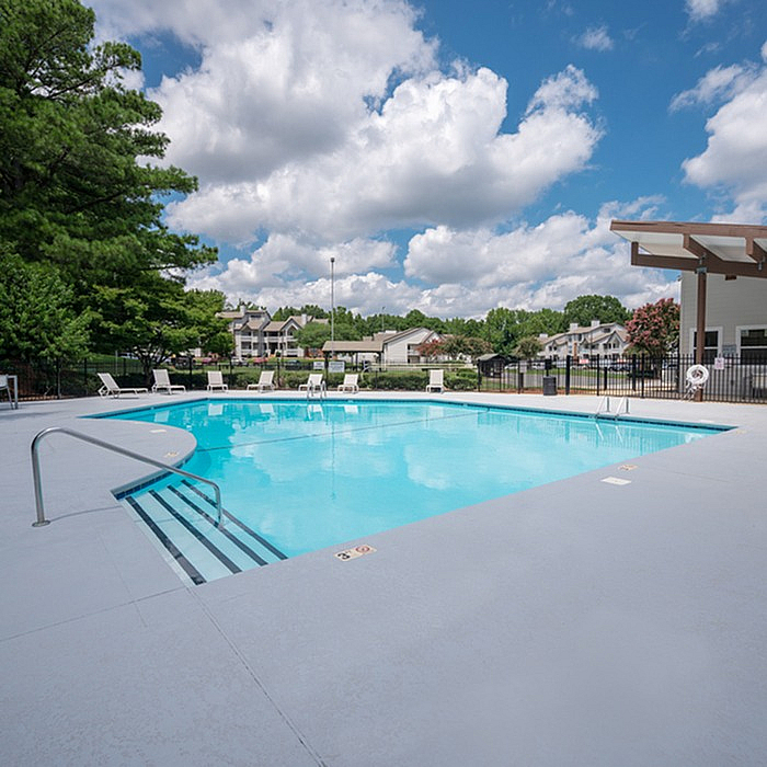 Inviting outdoor pool area with crystal-clear water, surrounded by lush greenery and modern sun loungers, perfect for relaxation and enjoyment.