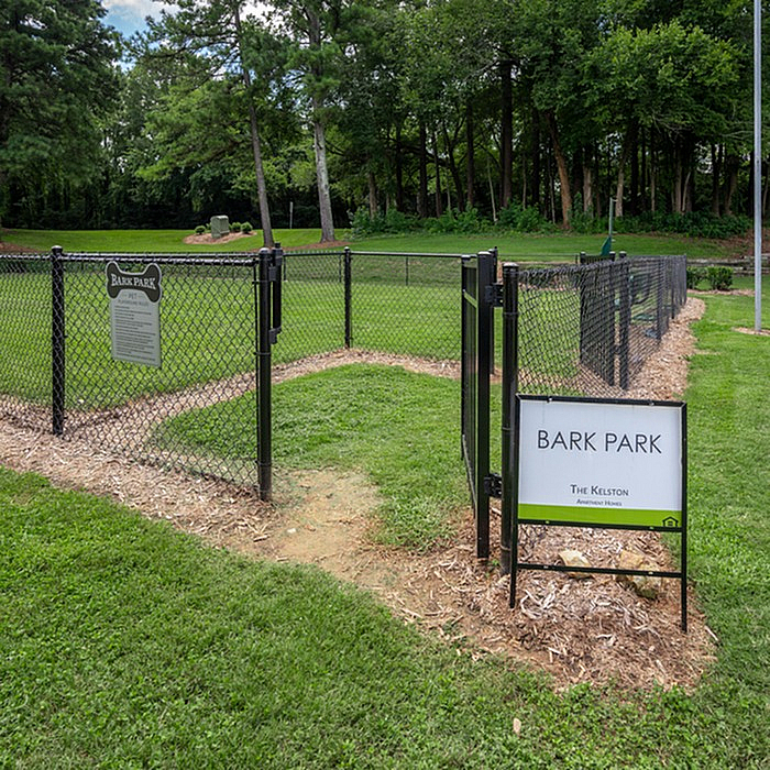 Inviting fenced Bark Park surrounded by lush greenery, ideal for dogs to play and explore.