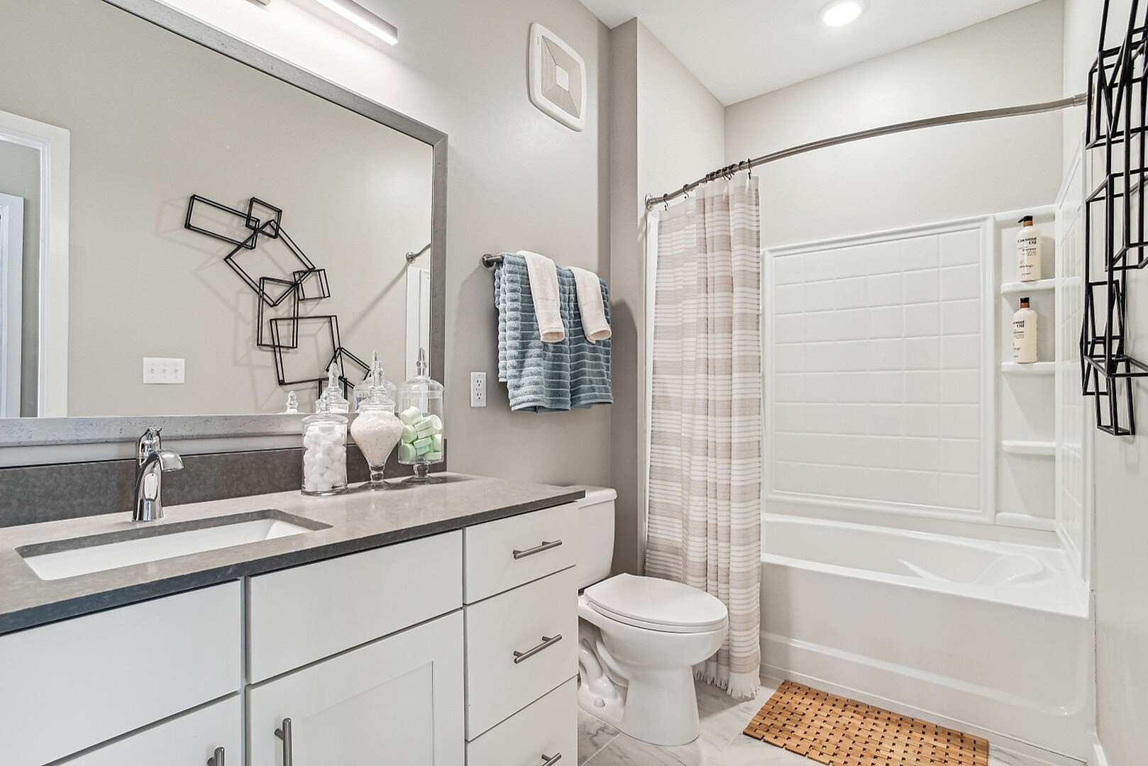 Modern bathroom featuring a sleek vanity with ample storage, contemporary lighting, and a stylish shower with decorative shelving.