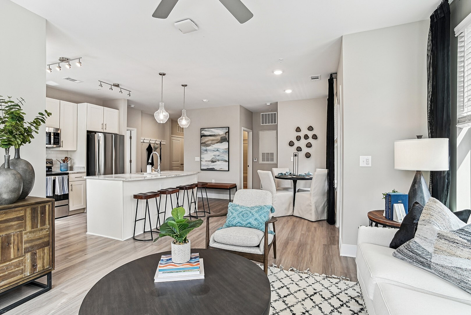 Bright open-concept living room with cozy seating, stylish dining area, and modern kitchen with sleek appliances.