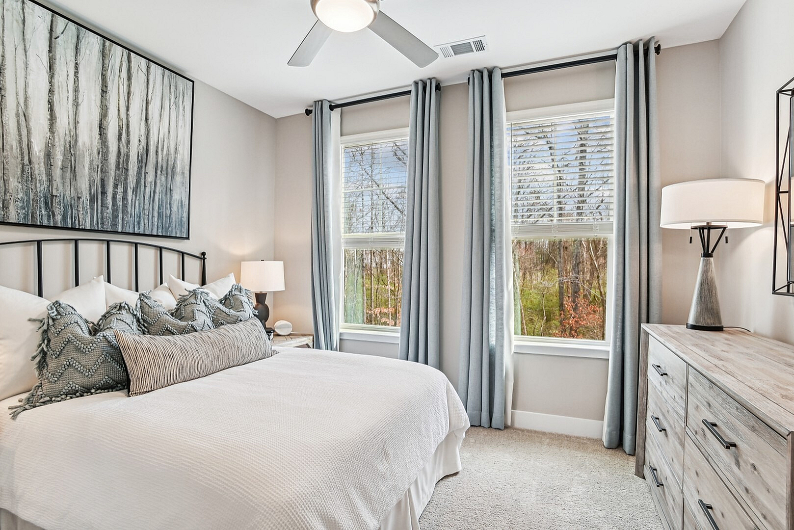Bright modern bedroom with stylish decor, featuring large windows and serene outdoor views.