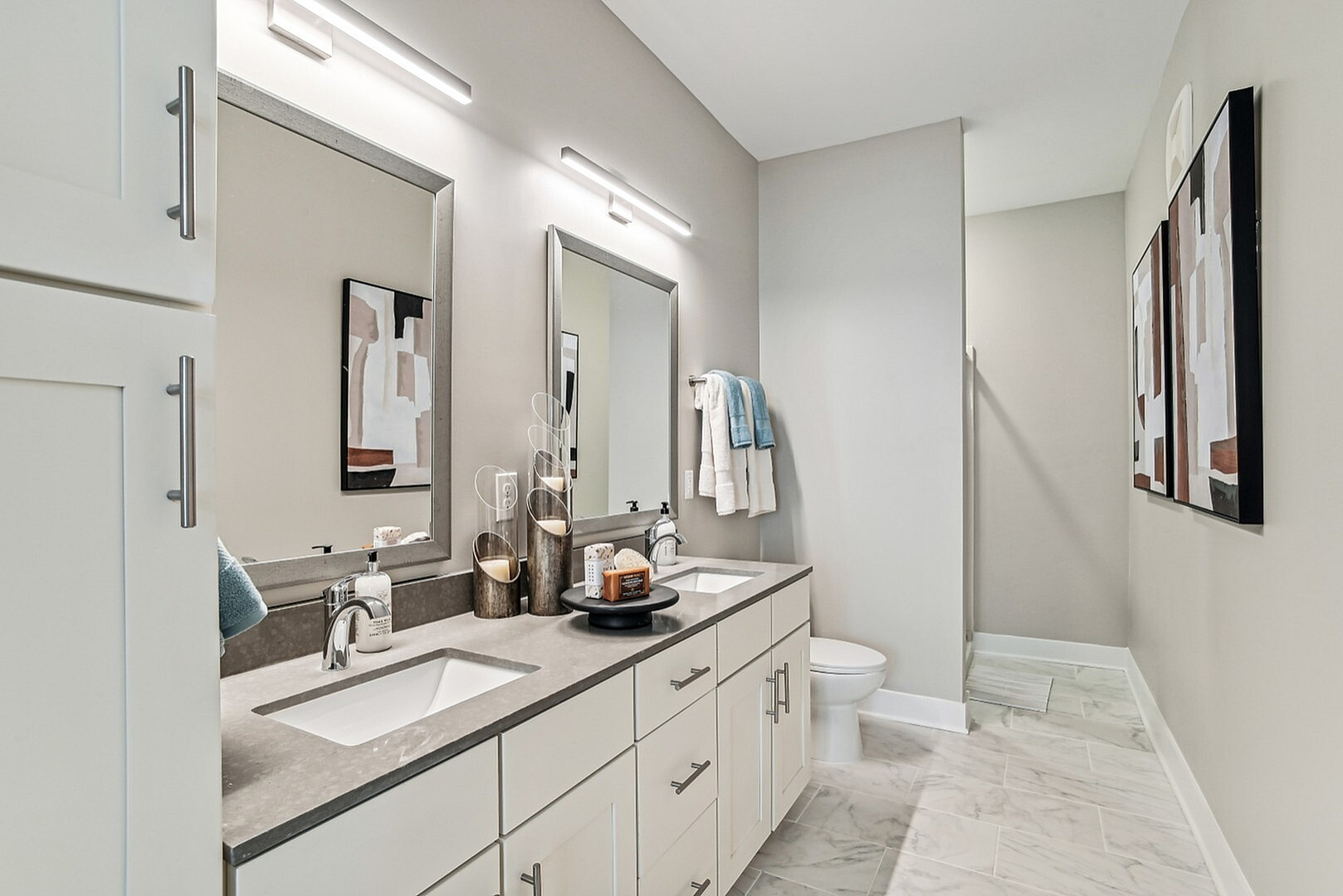 Modern bathroom featuring a sleek double vanity, elegant mirrors, and stylish abstract artwork.