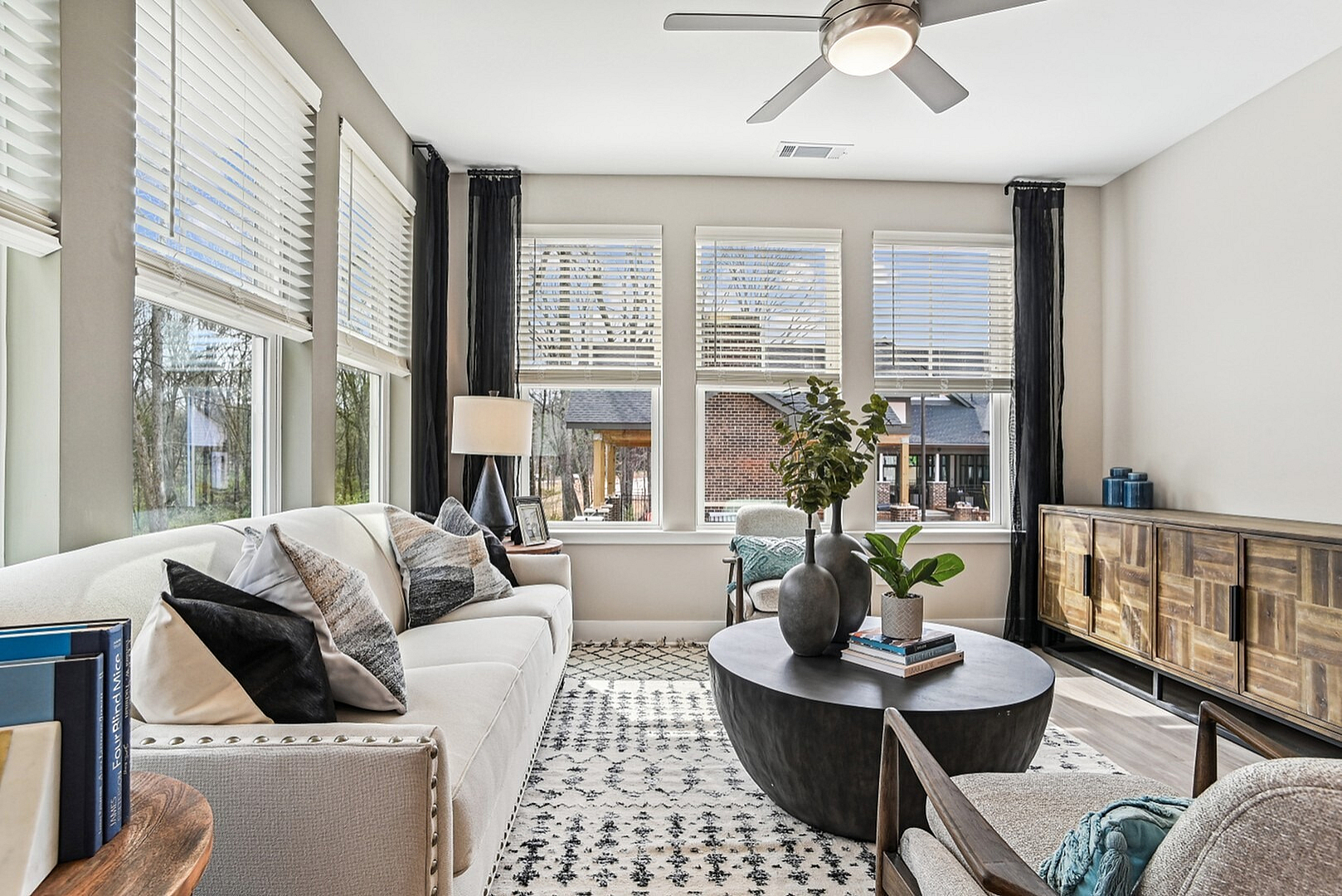 Bright and inviting living room with a chic modern design, featuring large windows, elegant furniture, and stylish decor.