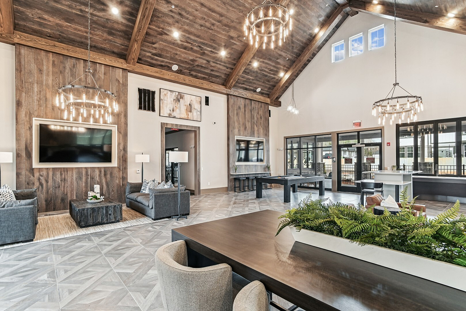 Luxurious open-concept living space with elegant chandeliers, plush seating, and a stunning vaulted ceiling, perfect for entertaining.