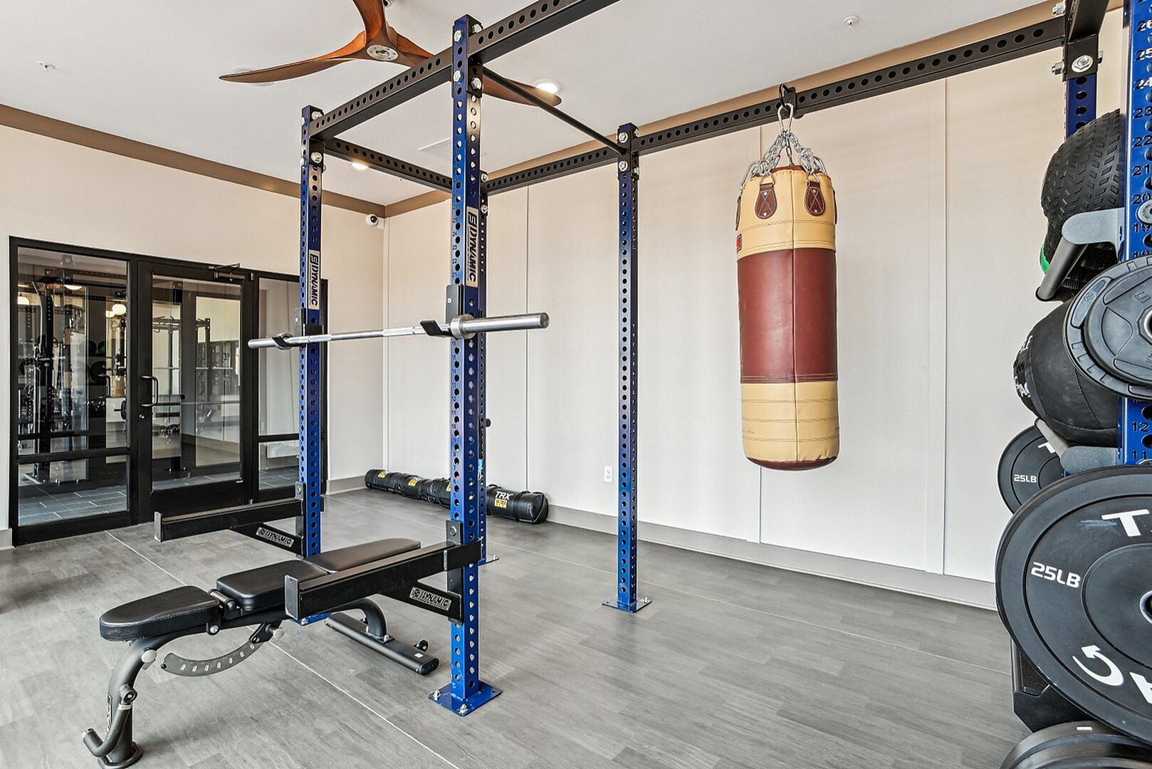 Modern fitness room with a sleek bench press setup, vibrant punching bag, and well-organized weight plates, perfect for dynamic workouts.