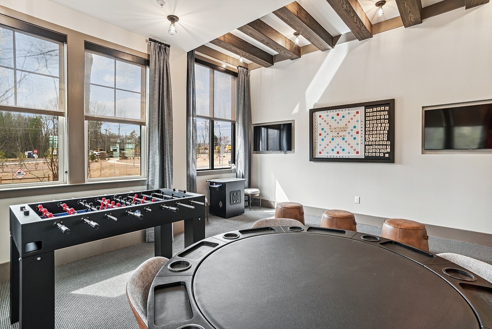 Elegant recreational room with a foosball table, stylish seating, large windows, and modern decor, ideal for entertainment and relaxation.