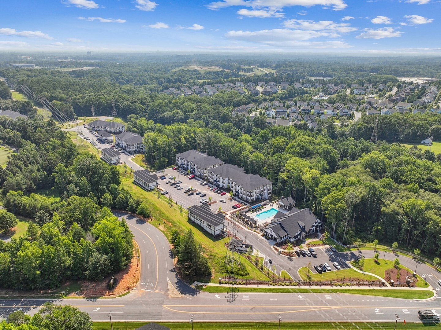 Stunning aerial view showcasing a luxurious apartment complex with a sparkling pool, surrounded by lush greenery and a serene residential neighborhood.