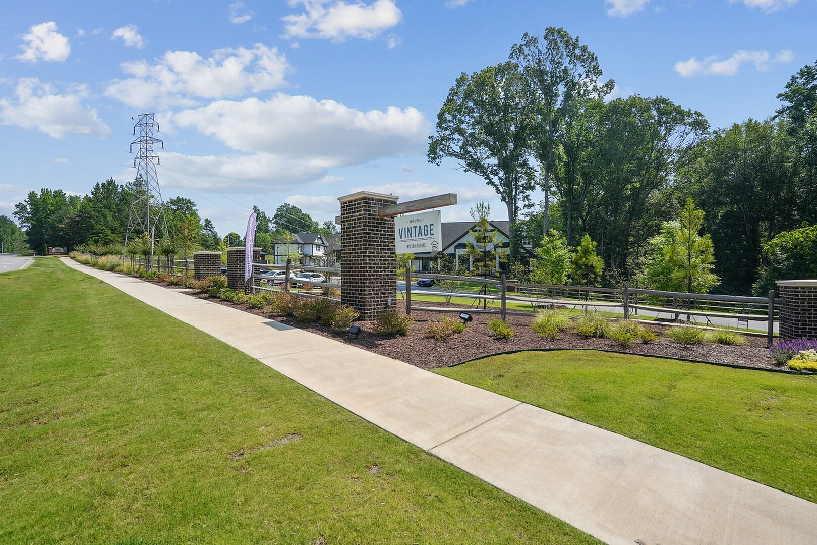 Inviting entrance to Vintage welcoming community, surrounded by lush greenery and vibrant landscaping under a clear blue sky.