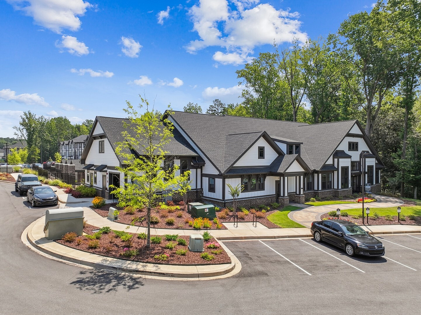 Charming modern duplex with lush landscaping, ample parking, and a serene wooded backdrop, perfect for tranquil living.