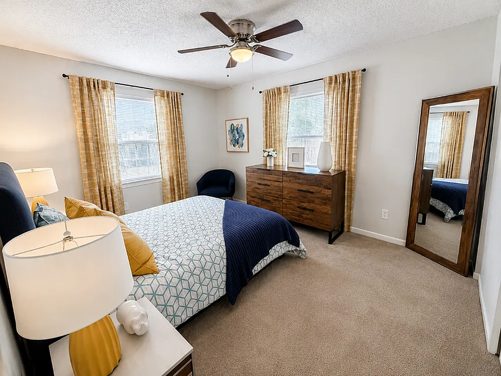 Bright and inviting bedroom with modern decor, featuring a cozy bed, stylish wooden dresser, and elegant full-length mirror.