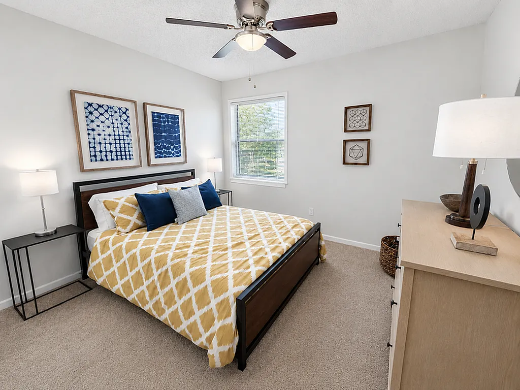 Bright and stylish bedroom with modern decor, featuring a cozy bed with vibrant yellow bedding, complementing artwork, and natural light from the window.