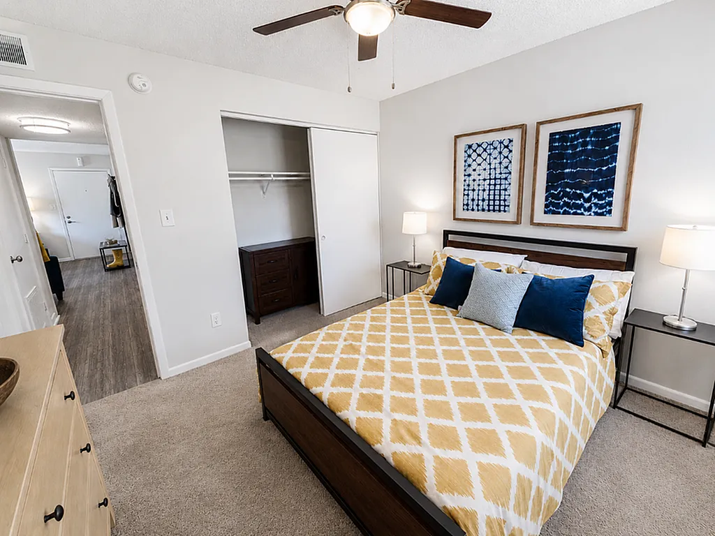 Inviting bedroom with modern decor featuring a patterned yellow bedspread, stylish artwork, and warm lighting.