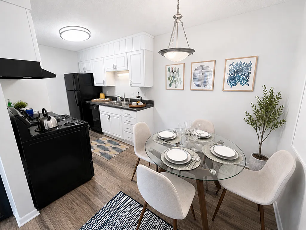 Modern kitchen and dining area featuring sleek black appliances, stylish glass dining table with set plates, and elegant wall art.