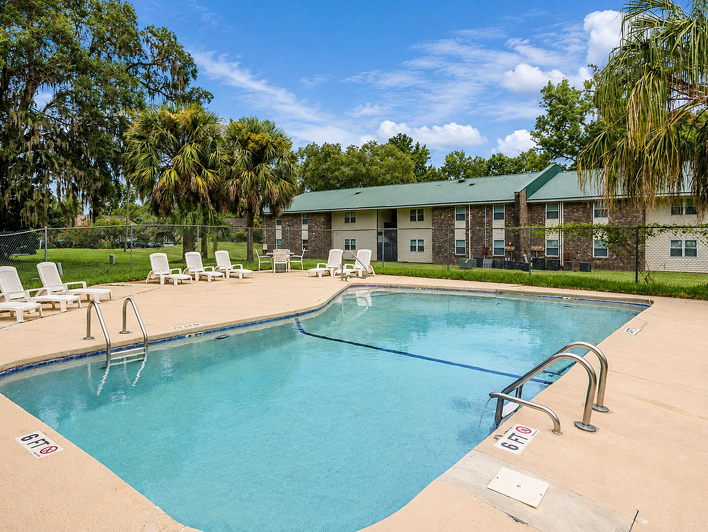 Inviting outdoor pool area with comfortable lounge chairs, surrounded by lush greenery and charming apartment buildings.