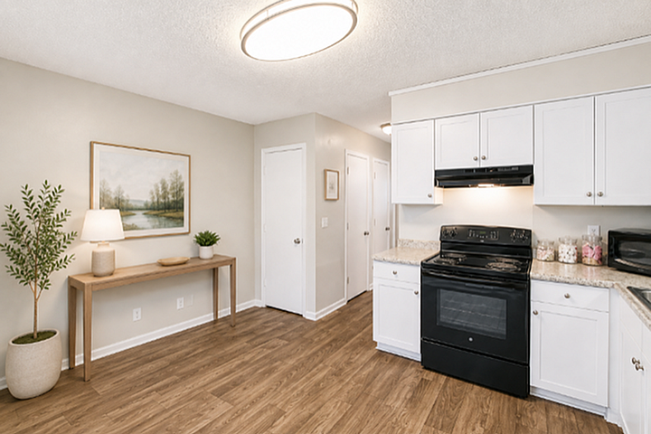 Elegant kitchen with modern black appliances, white cabinetry, and natural wood flooring, complemented by tasteful decor.