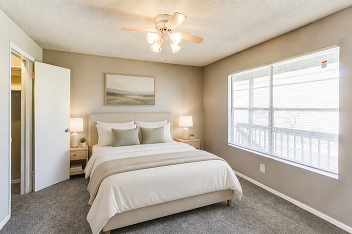 Elegant bedroom with soft lighting, featuring a cozy bed with plush pillows, warm neutral tones, and ample natural light from a large window.