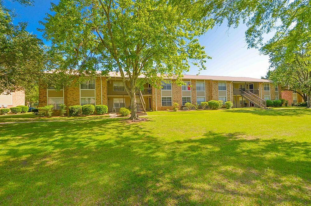 Charming apartment building with lush green lawns and mature trees, offering a peaceful residential environment with vibrant natural surroundings.