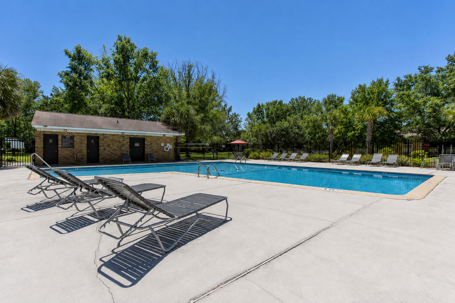 Inviting outdoor pool area with sun loungers and lush greenery, perfect for relaxation and leisure.