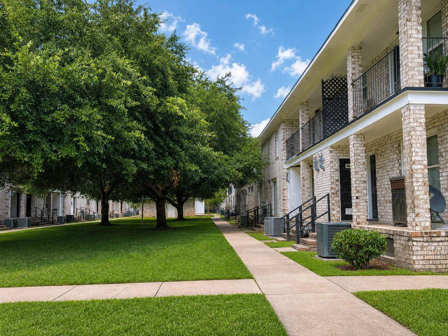 Inviting apartment complex with charming brick facades and lush green lawns, offering a serene residential environment.
