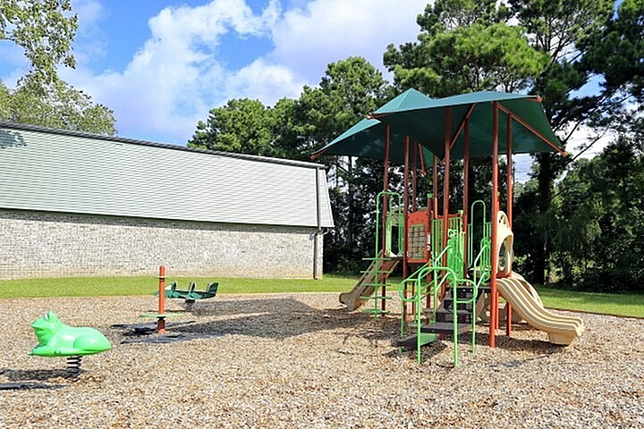 Inviting playground with vibrant play structures and swings, surrounded by lush greenery, perfect for family fun.