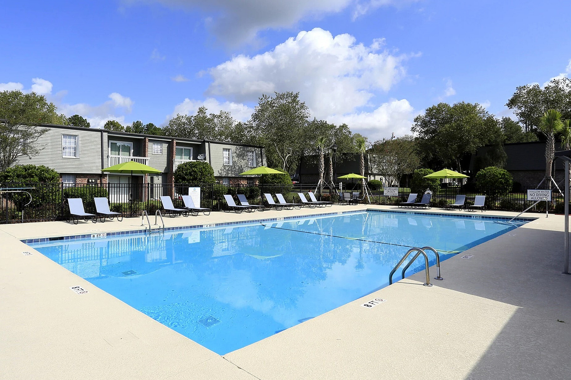 Inviting outdoor pool area surrounded by relaxing lounge chairs and vibrant green umbrellas, perfect for enjoying sunny days.