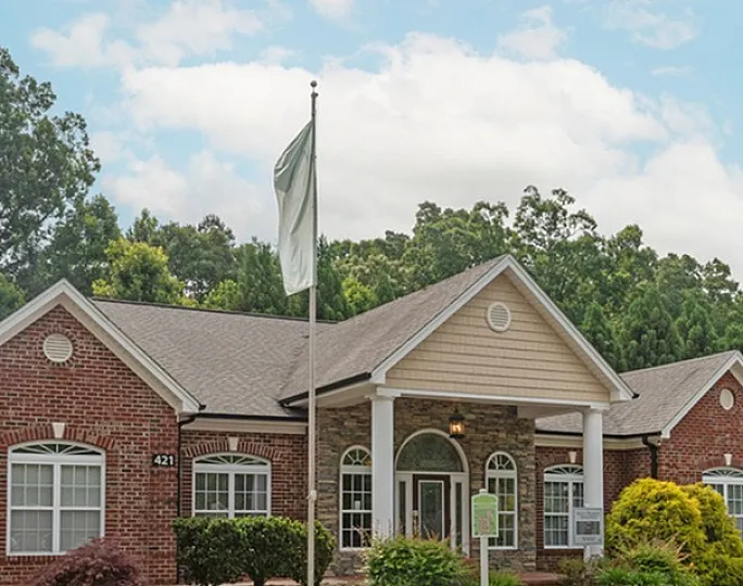 Inviting brick community building with classical architecture and lush landscaping.