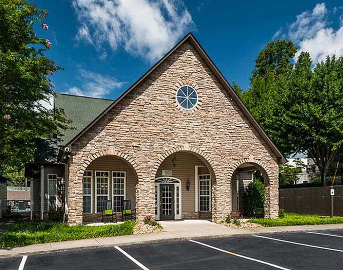Inviting building with a brown stone facade and arched entrances, set against a clear blue sky.