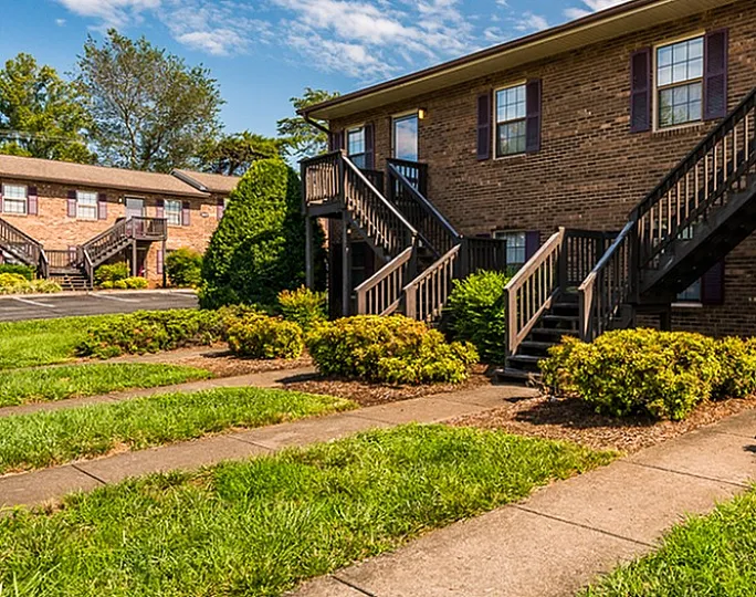 Inviting two-story apartment building with brick facade and lush landscaping.
