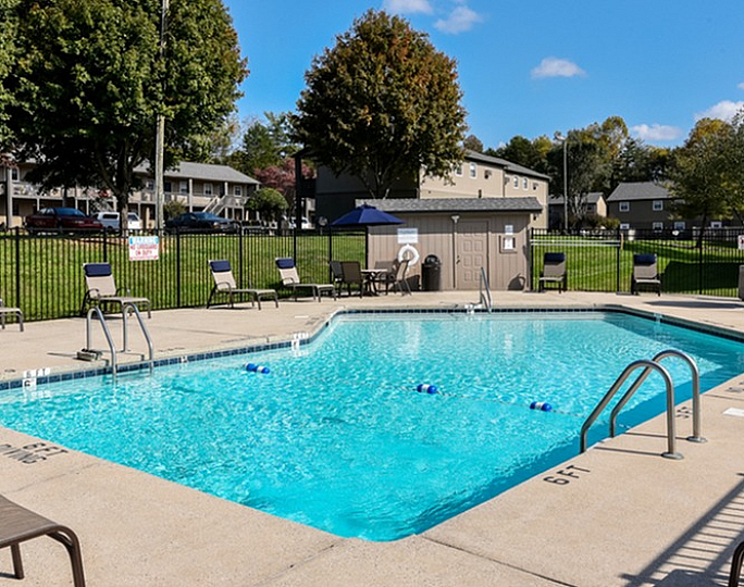Inviting outdoor community pool surrounded by lounge chairs and lush greenery.