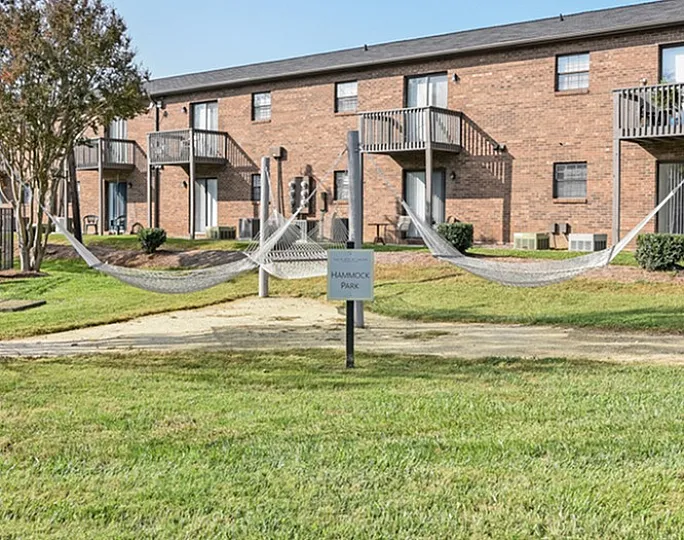 Peaceful apartment complex with charming balconies and hammocks in a green park setting.