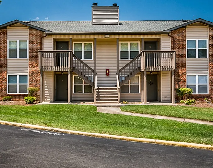 Inviting brick apartment building with two balcony entrances and manicured green lawns.