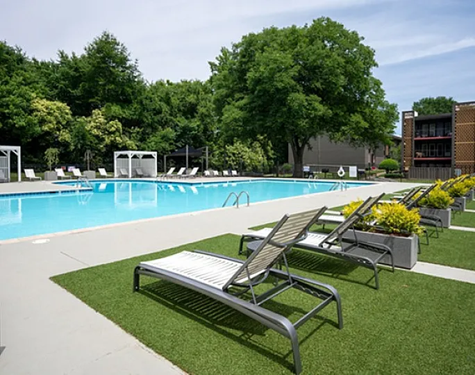 Inviting outdoor swimming pool surrounded by lush greenery and modern lounge chairs.